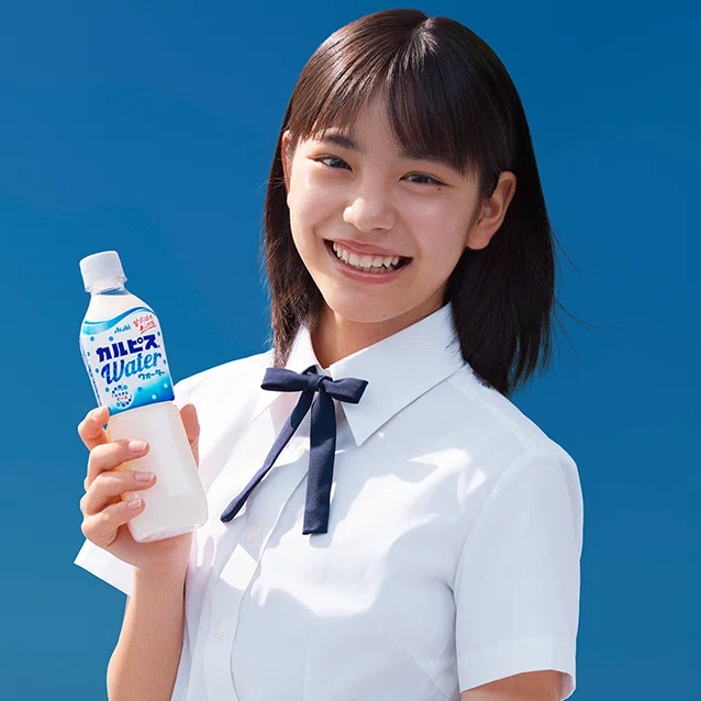 當真あみがカルピスを持って微笑んでいる写真